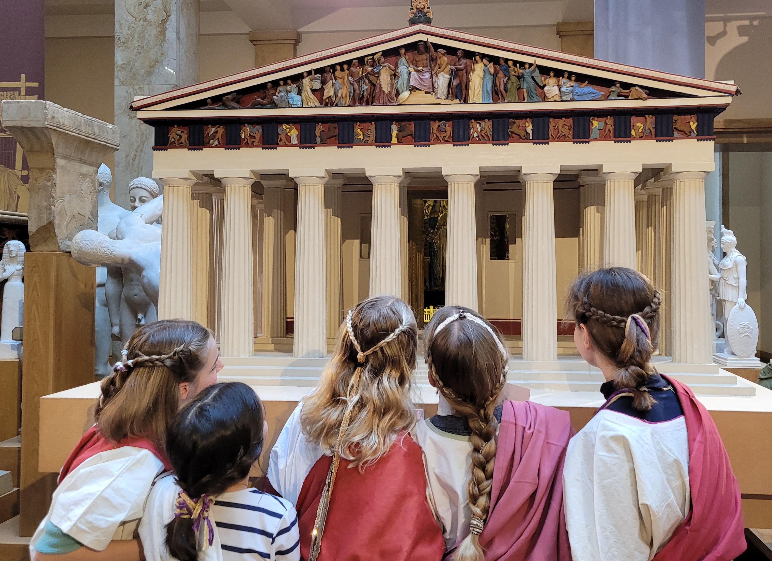 Verkleidete Kinder als Römer und Römerinnen blicken in das Innere des Parthenon-Modells