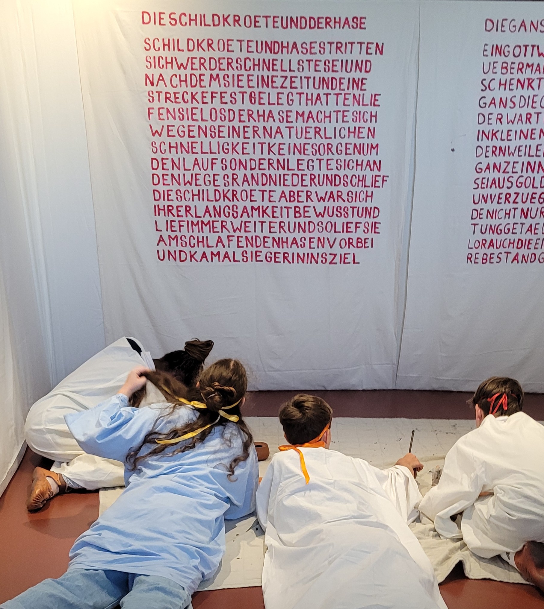 Kinder schreiben einen Text an der Wand ab
