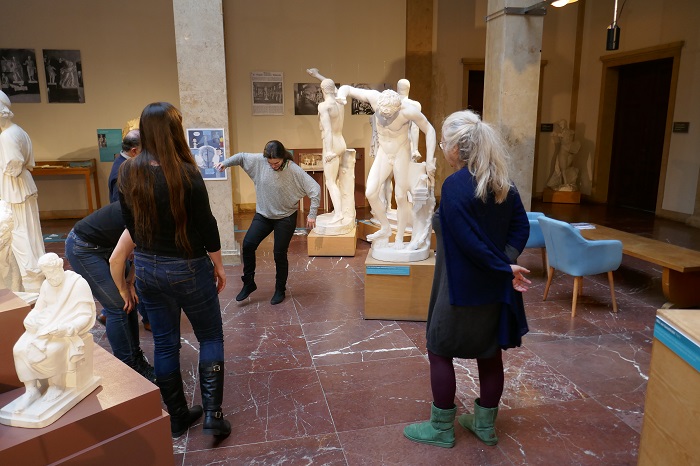 Besucherinnen stellen Posen der Statuen im Museum nach.
