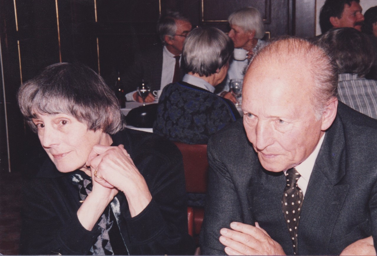 Eine ältere Frau und ein älterer Mann sitzen nebeneinander an einem Tisch